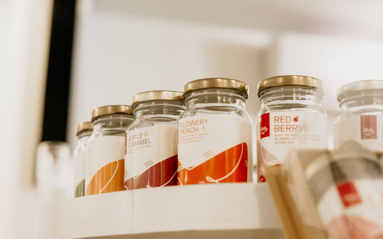A row of sealed glass fermentation jars on a kitchen shelf, labels handwritten with contents and date, ambient kitchen light