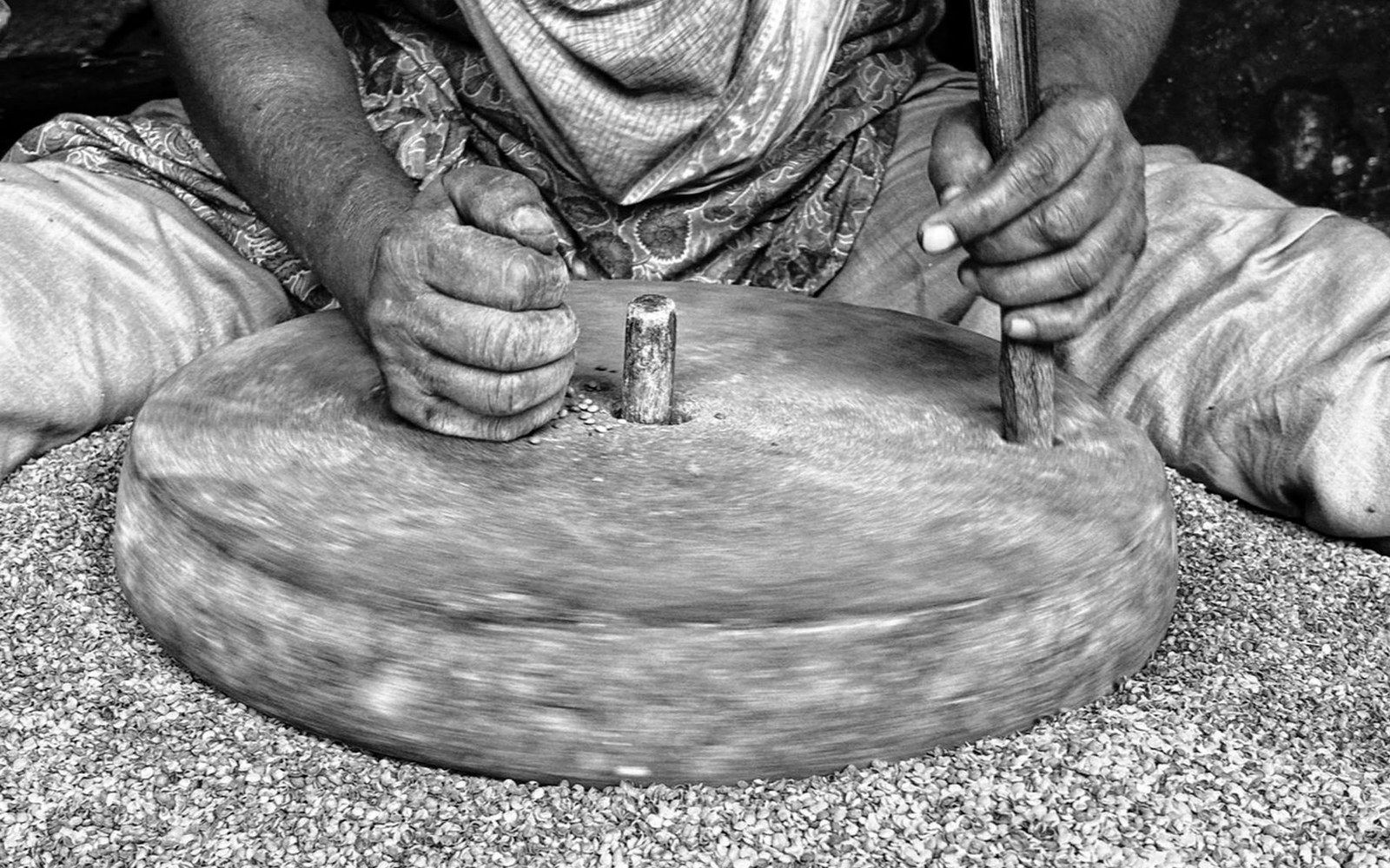 Hands turning a traditional stone mill to grind grain into flour