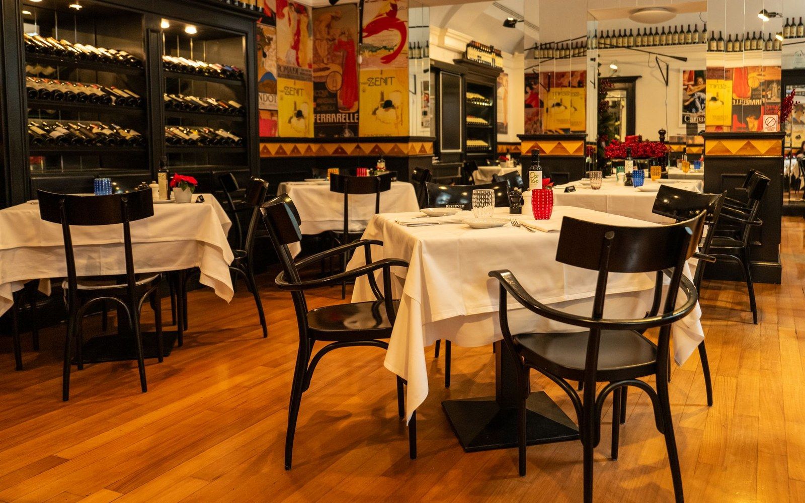 Restaurant dining room with white-clothed tables, bentwood chairs and wine bottles lining the shelves